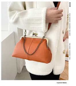 Close-up of pebble leather shell bag in orange with bronze clasp and chain strap