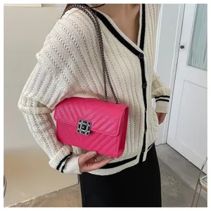 Detail of bright pink quilted crossbody bag with gemstone buckle and metal chain strap