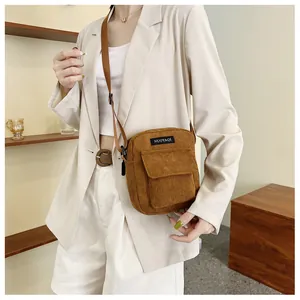 Detail of a brown corduroy crossbody bag featuring a front pocket and adjustable strap