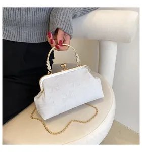 Elegant white vintage kiss-lock bag with bow patterns and floral metal handle detail