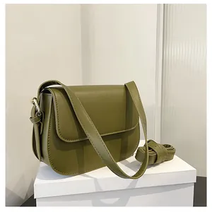 Olive green saddle bag detail with smooth matte texture and gold buckle on a white pedestal