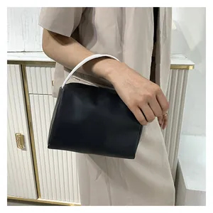 Close-up of minimalist black matte leather tote with unique white cylindrical handles