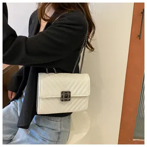 Detail of white embossed chain bag featuring a vintage square metal clasp with black gemstone