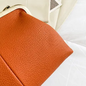 Detail of orange litchi grain leather and antique bronze metal clasp on shell bag
