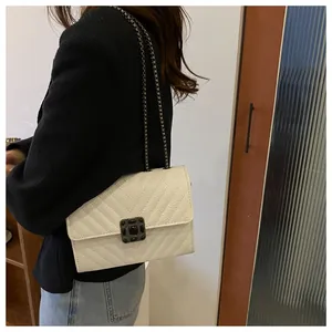 Detailed view of a white quilted shoulder bag with V-shaped texture and metal chain