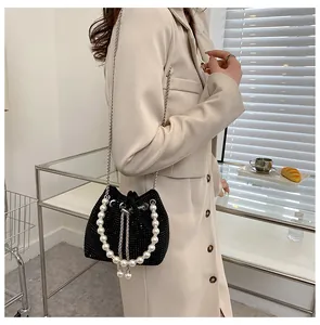 Detail of black drawstring bucket bag with sparkling rhinestones and pearl handle strap