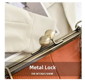 Close-up of vintage bronze hardware clasp on orange litchi pattern leather bag
