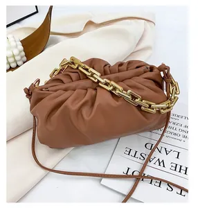 Detail of tan cloud bag featuring thick gold chain strap and pleated leather texture