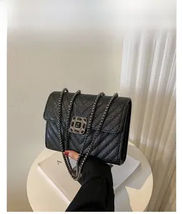 Close-up of black crossbody bag with V-shaped quilting and vintage metal buckle