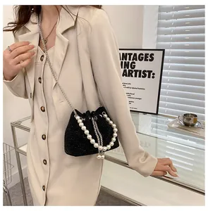 Close-up of black rhinestone bucket bag with pearl handle and metal chain strap