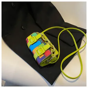 Detail of mini crossbody bag with multi-color mosaic patterns and neon green strap