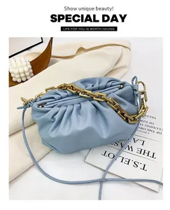 Close-up of light blue pleated cloud bag with chunky gold chain on a white blazer