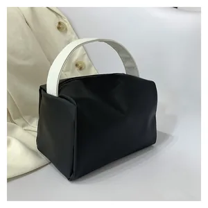 Detail of matte black minimalist handbag with contrast white handle and top zipper closure