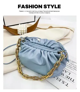 Detail of light blue pleated cloud bag with chunky gold chain on aesthetic background