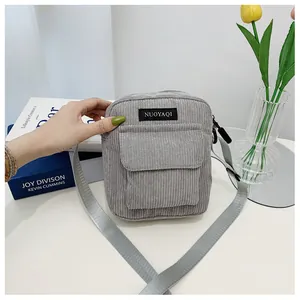 Detailed view of gray corduroy crossbody bag with adjustable strap and brand patch