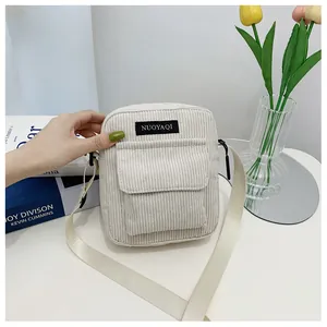 Detail view of cream corduroy crossbody bag with front pocket and adjustable strap