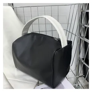 Detail of minimalist black bag with contrast white handle and matte leather texture