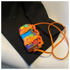 Detail shot of mini crossbody bag featuring mosaic pixel patterns and orange chain strap