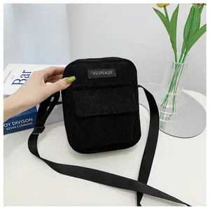 Detail of black corduroy crossbody bag featuring a front pocket and adjustable strap