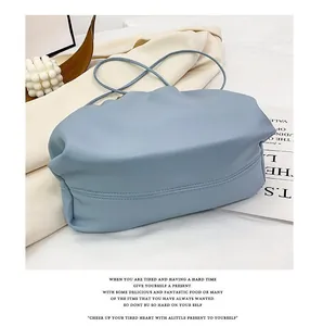 Close-up of light blue ruched cloud bag with fine shoulder strap and neat stitching