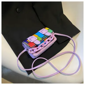 Detail of mini rainbow colorblock crossbody bag with purple buckles on black blazer