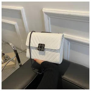 Detailed view of white pebble leather crossbody bag with V-shaped stitching and buckle