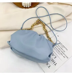 Close-up of light blue pleated cloud bag with chunky gold chain and leather strap