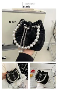 Close-up of black rhinestone bucket bag with large pearl handle and metal chain drawstring