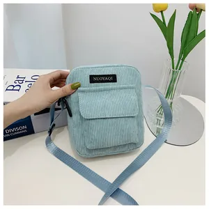 Close-up of light blue corduroy crossbody bag featuring a front pocket and adjustable strap