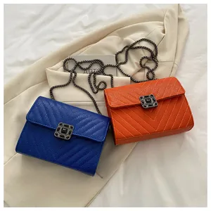 Detail view of V-quilted leather crossbody bags in blue and orange with chain straps