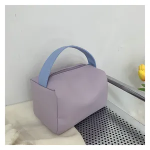 Detail of lavender makeup bag with light blue woven handle and zipper closure on tray