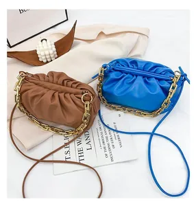 Close-up of pleated leather cloud bags in blue and brown with thick gold metal chains