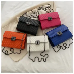 Flat lay of colorful V-quilted faux leather crossbody bags with metal chain straps