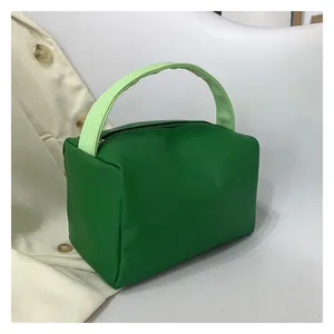 Detail of green square tote bag with textured lime green handles and zip closure