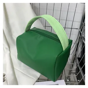 Detail of lime green crossbody bag with textured handle and zip closure on white fabric