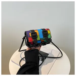 Detailed close-up of a colorful mosaic crossbody bag with dual buckles and a black chain link