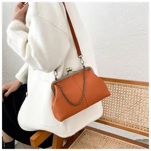 Detailed shot of bright orange lychee leather shell bag with metal clasp and chain strap