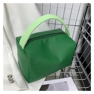 Detail view of the green crossbody bag showing zipper closure and woven handle texture