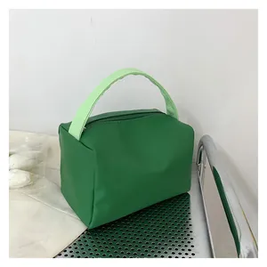 Detail of dark green cosmetic bag with light green top handle on metallic chair