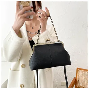Detail of black lychee texture shell bag with gold clasp and elegant chain strap