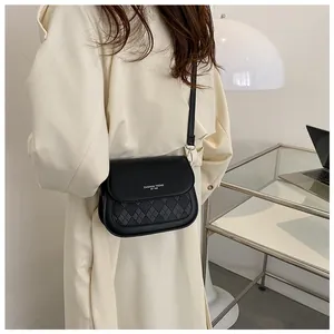 Detail of black faux leather saddle bag featuring quilted pattern and fashion text logo