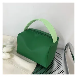 Detail view of a green rectangular crossbody bag with dual-tone handles and smooth zipper