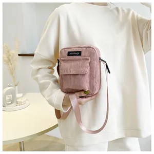 Detail of pink corduroy crossbody bag texture and branded logo with nylon strap