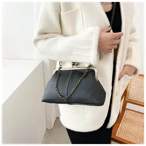 Detail of black lychee grain shell bag with vintage metal clasp and chain strap