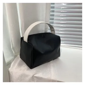 Detail of a minimalist black and white square tote bag with wide top handle near a window
