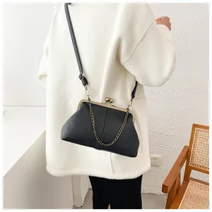 Detail of black litchi texture shell bag with gold clasp closure and chain strap