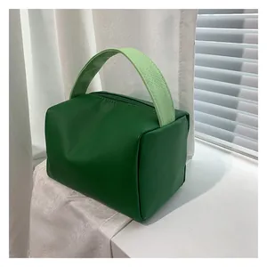 Detail of green PU leather handbag featuring textured woven handles and zipper closure