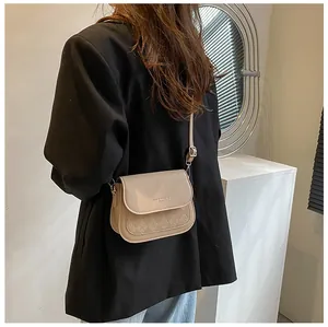 Detail of beige saddle bag with diamond pattern quilting and Fashion Trend lettering