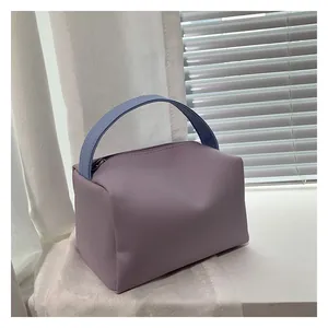 Detail view of the lavender handbag with a blue textured handle and smooth matte finish