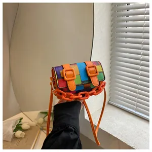 Close-up of color-block mini crossbody bag with orange chains and leather strap